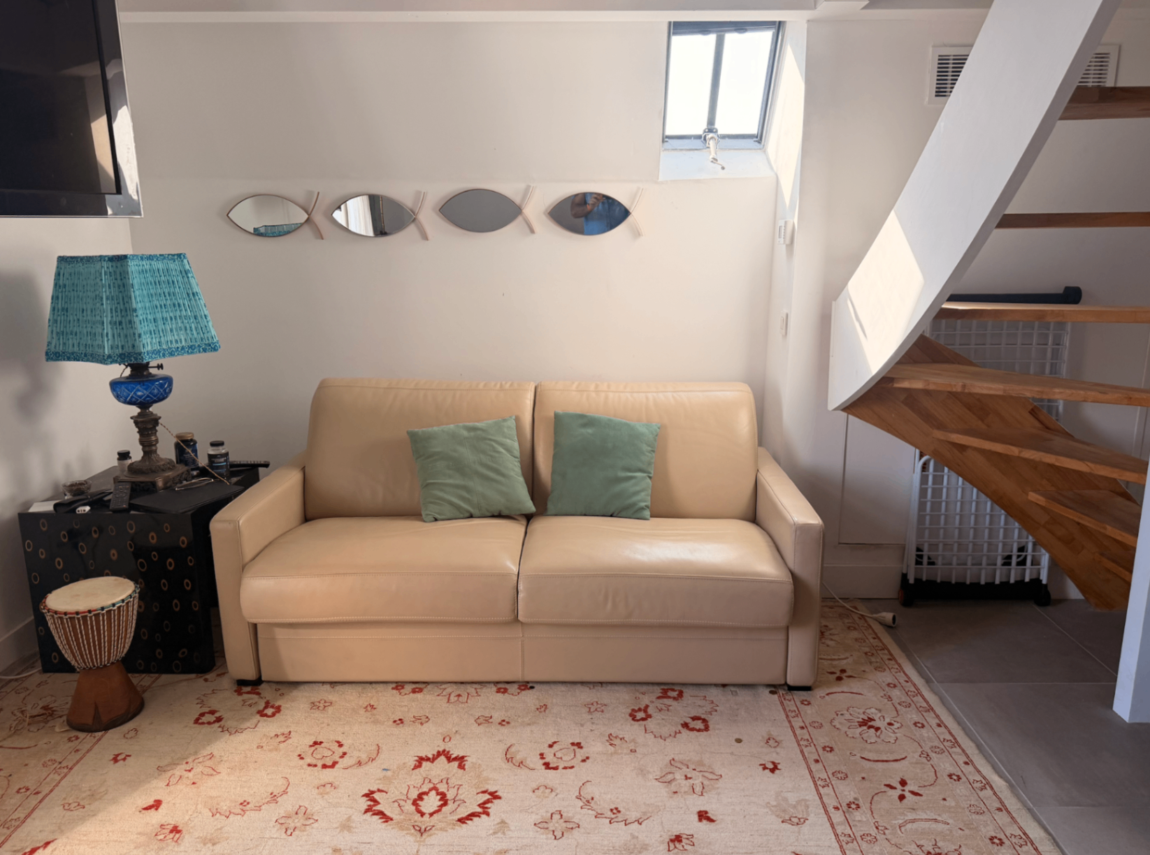 Sitting area with cream sofa, turquoise lamp and staircase detail