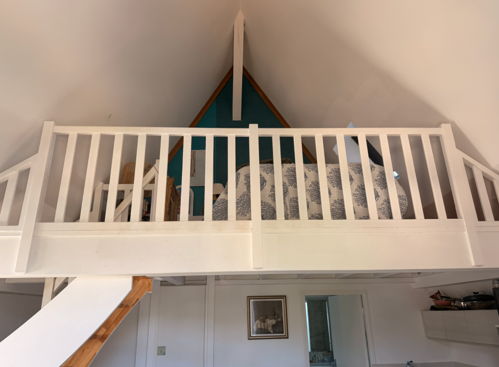 A-frame loft gable with teal accent wall behind the bed