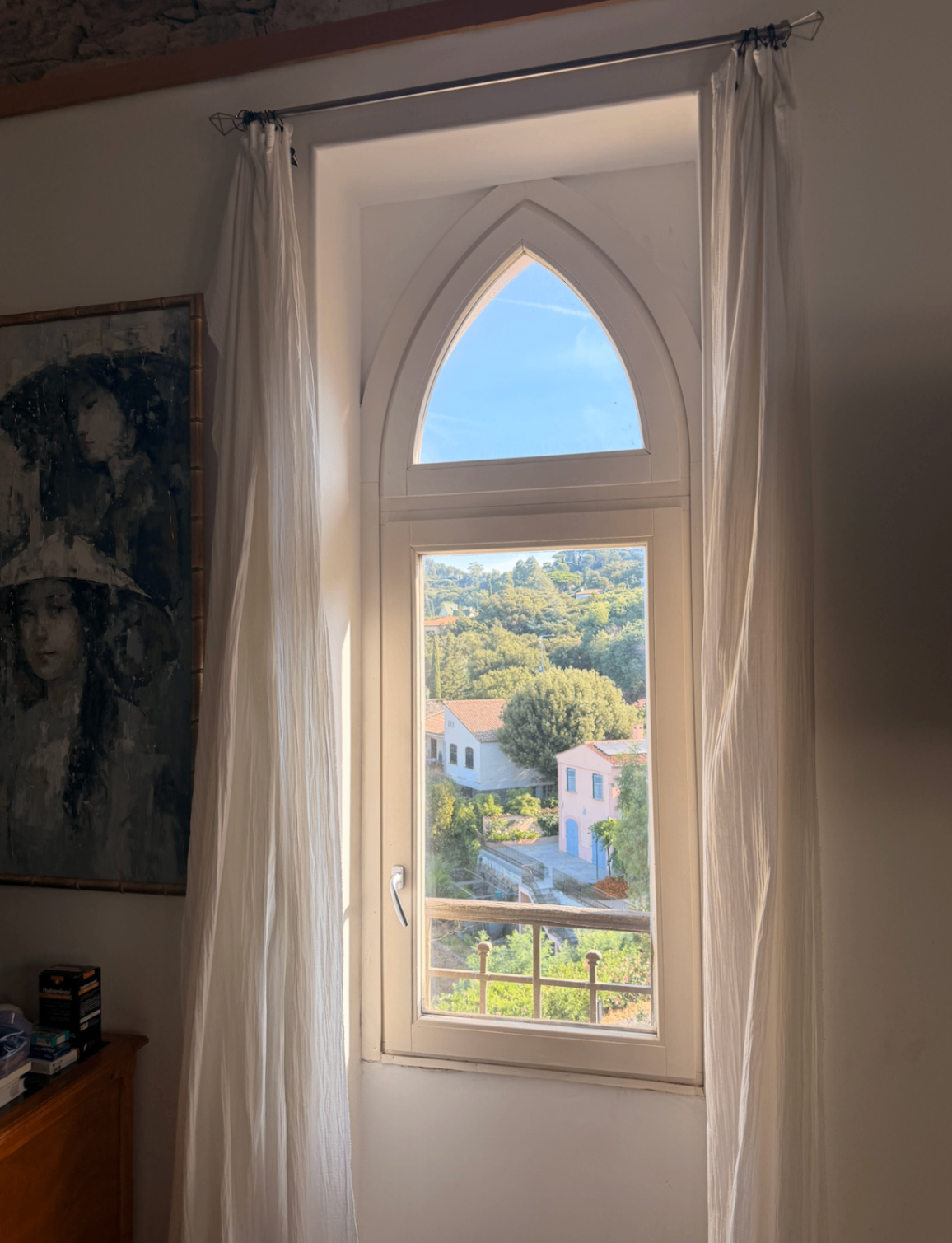 Tall arched window with sheer curtains and garden outlook