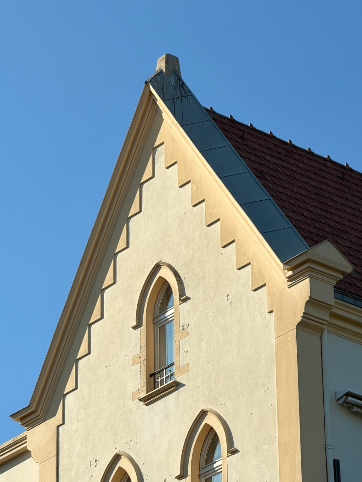 Ornate gothic gable and terracotta roof against a deep blue sky