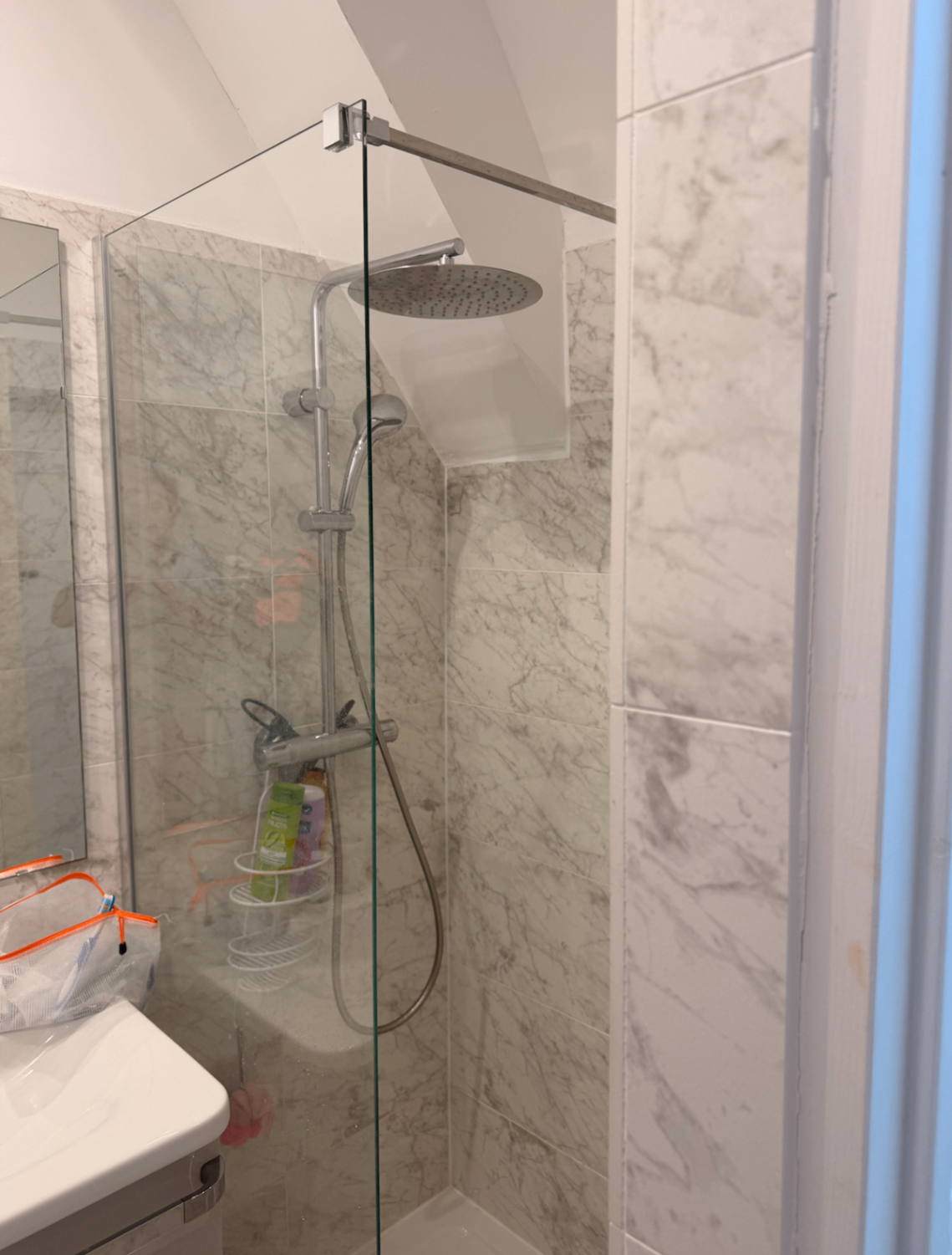 Walk-in marble shower with rainfall head under the eaves
