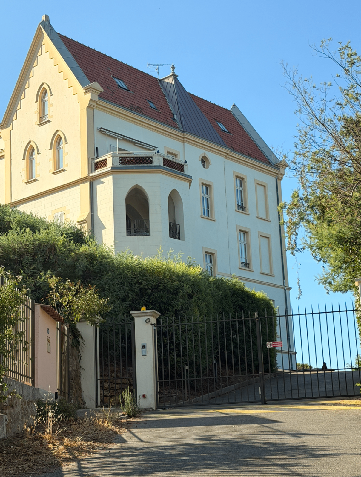 Full facade of the historic residence rising above the gated drive