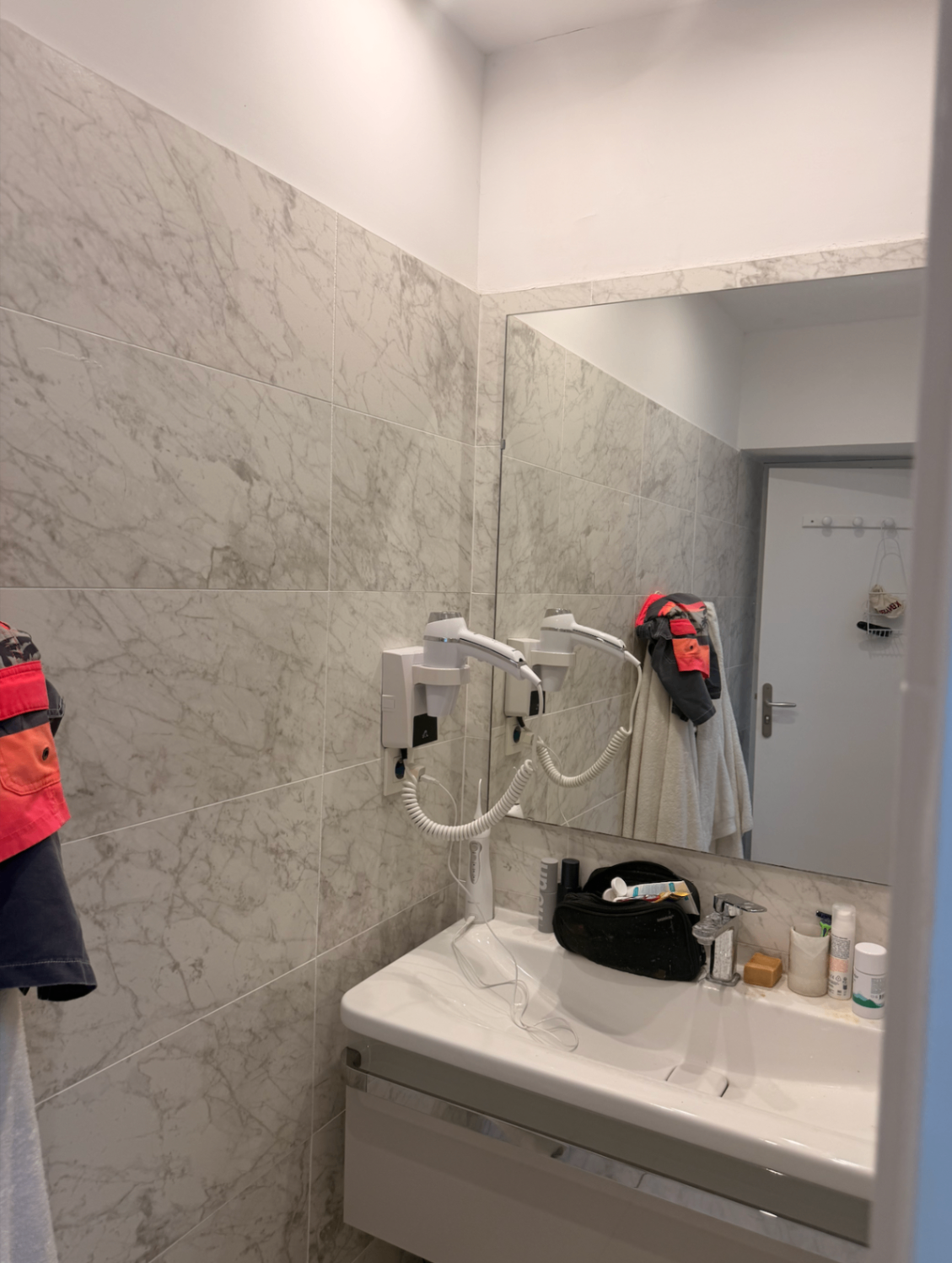 Marble-clad bathroom with vanity, mirror and hair dryer