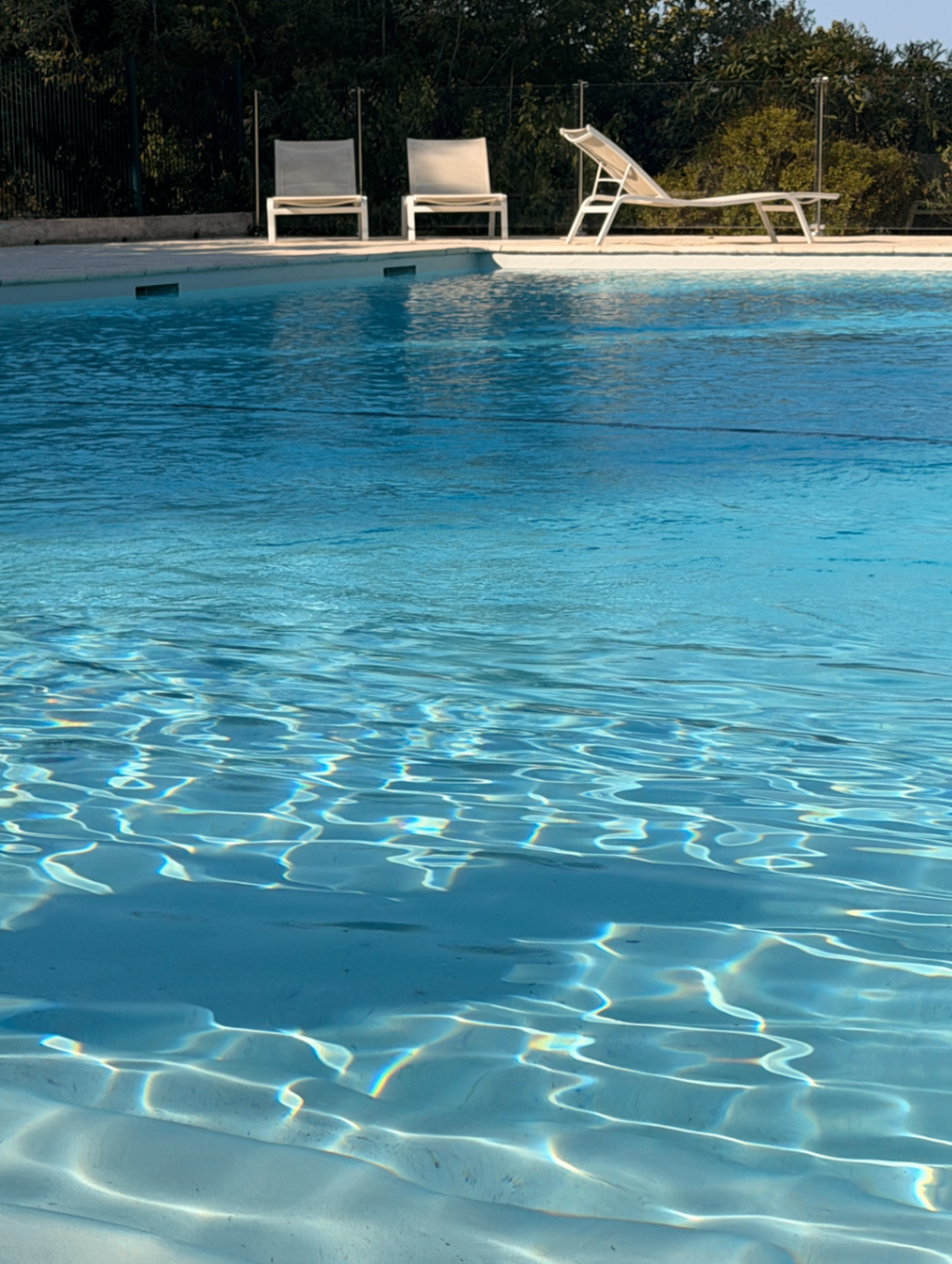 Close-up of crystalline pool water with white loungers at the edge
